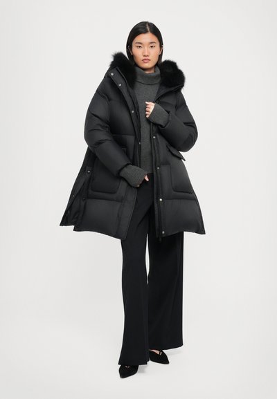 Black puffer coat with a faux fur hood; features a zip and snap closure, side pockets, and a slightly longer, oversized fit.