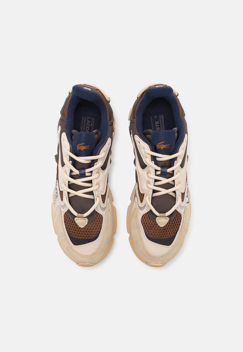 Trampki Lacoste charakteryzują się połączeniem brązowej i beżowej siateczki oraz zamszu, z beżowymi sznurówkami i gumowymi podeszwami. Logo jest wyraźnie widoczne.