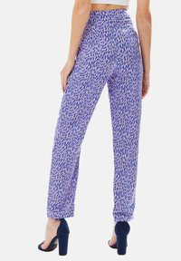 Purple patterned trousers with a loose fit, featuring multicolored abstract shapes. Smooth fabric with a high waist and straight legs.