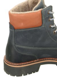 Dark blue leather boot with a tan leather collar, beige fuzzy lining, gray stitching, and a textured rubber sole. Eyelets and laces included.