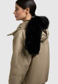 Giacca imbottita beige con cappuccio in pelliccia sintetica nera, dotata di chiusura con zip, tasche laterali e finitura opaca.