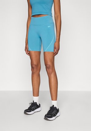 Shorts de sport turquoise avec une taille haute et des détails sur les coutures latérales. Associés à des chaussures de sport noires et des chaussettes blanches montantes.