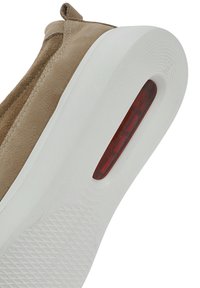 Beige suède sneakers met een witte rubberen zool en een rode doorschijnende detail. Glad oppervlak met een ronde hak en minimale stiksels.