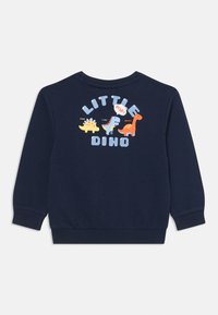 Laivastonsininen collegepaita, jossa on värikkäitä dinosauruskuvastoja ja teksti "LITTLE DINO." Ribbed hihansuut ja helma pehmeästä, teksturoidusta kankaasta.
