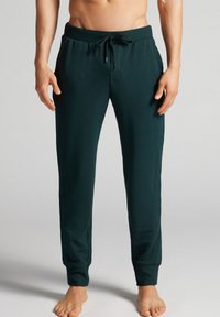 Donkergroen joggerbroek gemaakt van zachte stof, met een elastische tailleband met een trekkoord en taps toelopende benen met gestreepte boordjes.