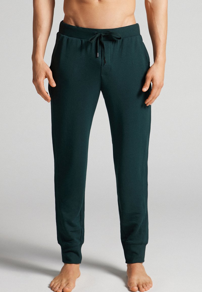 Donkergroen joggerbroek gemaakt van zachte stof, met een elastische tailleband met een trekkoord en taps toelopende benen met gestreepte boordjes.