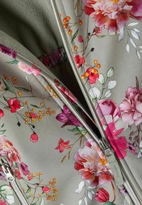 Blommig zip-up jacka i mjukt grått tyg, med rosa och orange blommor, gröna blad och en silverfärgad dragkedja med detaljer i metall.