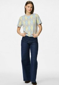 Camisa de pantalón corta azul claro con un patrón de rombos amarillo y azul, combinada con jeans de pierna ancha azul oscuro. Textura de tela suave.