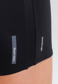 Musta urheilushortsit, joissa on tekstuuri, ja joissa on sivuilla vastakkaisella valkoisella kirjoituksella "adidas running" ja "climacool" -tunnukset.