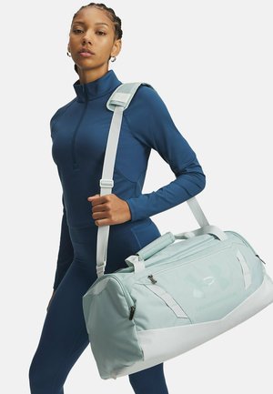 Light blue duffle bag with handles and an adjustable strap, featuring a smooth fabric texture and prominent logo on the front.