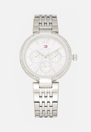 Silver-tone watch with a round white dial, three subdials, and a crystal-accented bezel. Features a stainless steel link bracelet.