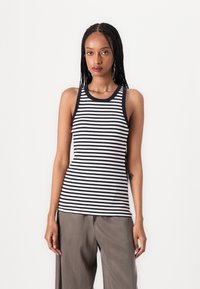 Navy and white striped tank top with sleeveless design and round neckline, paired with loose grey pants, showcasing soft cotton texture.