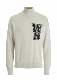 Krämfärgad stickad polotröja med ribbade ärmslut och nederkant, med stora svart konturerade bokstäver "WS" på vänster bröst.