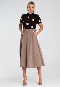 Czarny dzianinowy top z różowym haftem kwiatowym, zestawiony z beżową spódnicą o wysokim stanie z paskiem i kieszeniami.