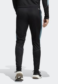 Černé sportovní kalhoty s světle modrými bočními pruhy, zúžený střih, vyrobené z hladkého syntetického materiálu, s vyšitými akcenty a pohodlným pasem.