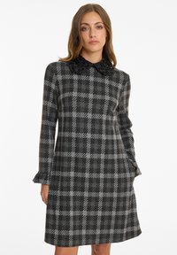 Gray checkered dress with a textured black beaded collar, long sleeves, and a flared hemline, made from a soft fabric.