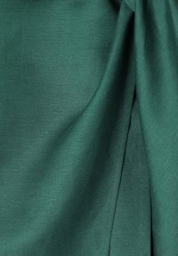 Tela verde con una textura suave, que presenta pliegues sutiles y un ligero brillo. El material parece liviano y finamente tejido.