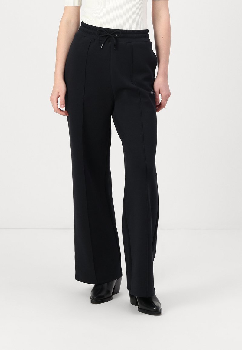 Schwarze weite Hose aus weichem Stoff, mit einem elastischen Taillenbund und einem Kordelzug sowie einer glatten Textur.