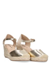 Wedges de esparto dorados con un acabado metálico, suelas de yute trenzado y correas en el tobillo. Textura suave con un diseño de punta redondeada.