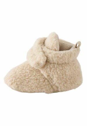 Weicher beiger Baby-Bootie aus strukturiertem Fleece-Stoff mit einer Schlaufe hinten und einem umgeschlagenen Bündchen um den Knöchel.