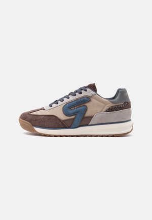 Baskets décontractées avec panneaux en daim marron, beige et bleu, lacets foncés et semelle blanche rembourrée avec un dessous texturé.