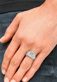 Anello d'argento con un design circolare che presenta un foro centrale e incisioni di testo. Superficie texturizzata, larghezza media, indossato su una mano.