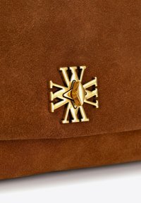 Bruine suède handtas met een opvallende gouden sluiting met een ingewikkeld ontwerp. Glad textuur met een zachte afwerking.