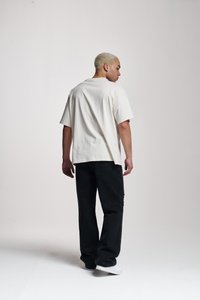 Overdimensjonert hvit bomull t-skjorte med rund hals, i kombinasjon med løse svarte denimbukser, med rette bein og sidelommer.