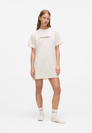 Robe T-shirt beige clair à manches courtes, décolleté arrondi et petit logo noir "KARL LAGERFELD". Port�ée avec des chaussettes assorties.