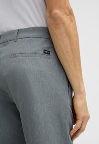 Pantaloni grigi, texturizzati, con una vestibilità dritta. Presentano una tasca posteriore con etichetta e una vita piatta. Design semplice e moderno.