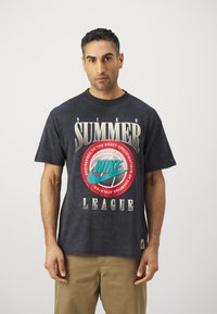 Svart grafisk t-skjorte med fet hvit og rød tekst, en turkise Nike-logo, og et basketballmotiv; kort erm, laget av bomull.
