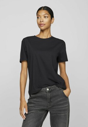 T-shirt noir à manches courtes en tissu doux avec un col rond classique, associé à un jean taille haute gris foncé avec des poches avant.