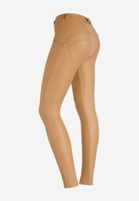 Leggings color nocciola realizzati in materiale testurizzato, con un design aderente, tasche frontali e cuciture a contrasto lungo i lati.