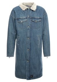 Abrigo de mezclilla de color azul claro, con cuello blanco esponjoso, dos bolsillos en el pecho, bolsillos laterales y cierre con botones de presión. Mangas largas y corte holgado.