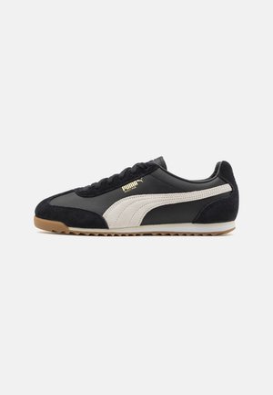 Sort lavt Puma-sneakers med hvid sidelinje, gummisål, ruskindsdetaljer og guld "Puma Arizona" logo på siden.