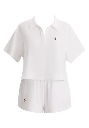 Λευκό πόλο τοπ με κοντά μανίκια και V-λαιμόκοψη, συνδυασμένο με σορτς στο ίδιο χρώμα. Διαθέτει μικρό μαύρο λογότυπο στο στήθος και στα σορτς. Μαλακή υφή.