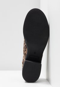 Bottine en imprimé léopard avec un dessus texturé marron et une semelle en caoutchouc noire, dotée d'un petit talon et sans détails métalliques visibles.