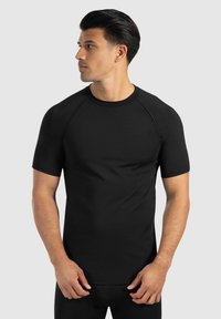 Schwarzes kurzärmliges körperbetontes T-Shirt aus glattem Stoff mit rundem Ausschnitt und Raglanärmeln, entworfen für Komfort und Beweglichkeit.