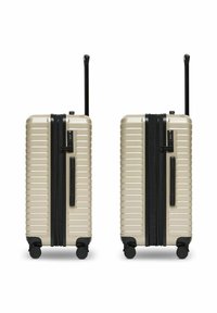 Twee beige harde koffers met zwarte handvatten, ritsen, ingebouwde TSA-sloten en uitklapbare telescoophandvatten, naast elkaar weergegeven.