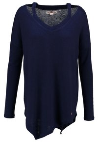 Haut à manches longues bleu marine avec un col en V, texture douce, ourlet asymétrique et un petit détail d'étiquette en bas à gauche.