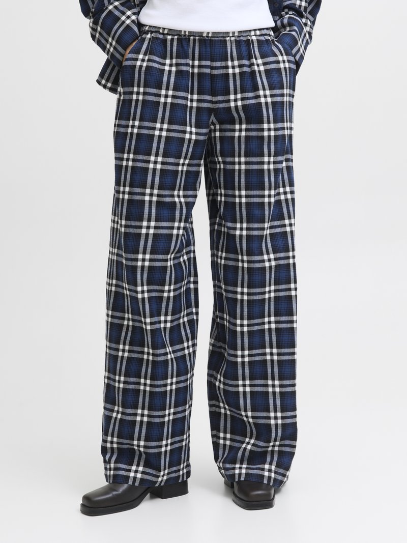 Calças largas em xadrez nas cores azul-marinho, branco e preto, com padrão quadriculado, cintura elástica e bolsos laterais.