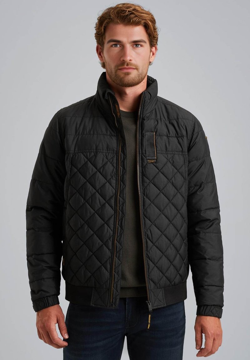Zwarte gewatteerde jas met een staande kraag, ritssluiting aan de voorkant en zichtbare stikseldetails. Bevat ribbels bij de manchetten en heeft een iets cropped pasvorm.