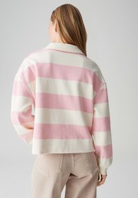 Roze-wit gestreepte trui met een kraag en een ontspannen silhouet. Gemaakt van zachte stof, voorzien van lange mouwen.