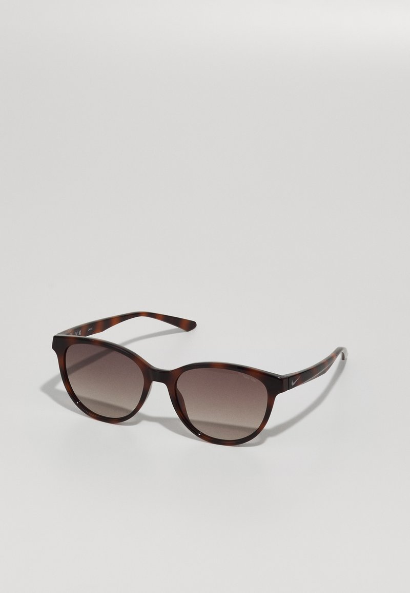 Lunettes de soleil écaille de tortue avec une monture ronde et des verres dégradés. Elles présentent des branches fines avec un discret détail de logo.
