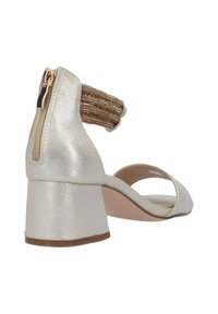 Sandalo con tacco dal finish metallico argento, un tacco spesso e un cinturino alla caviglia texturizzato dorato. Presenta una zip laterale per la chiusura.