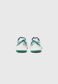 Weiße Sportschuhe mit grünen und marineblauen Akzenten. Texturierte Ferse für besseren Halt, atmungsaktives Mesh-Obermaterial und gepolsterte Sohle. Minimalistisches Design.