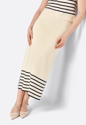 Knee-length, cream-colored knit skirt with navy horizontal stripes at the hem. High waist design, showcasing a smooth texture and fitted silhouette.