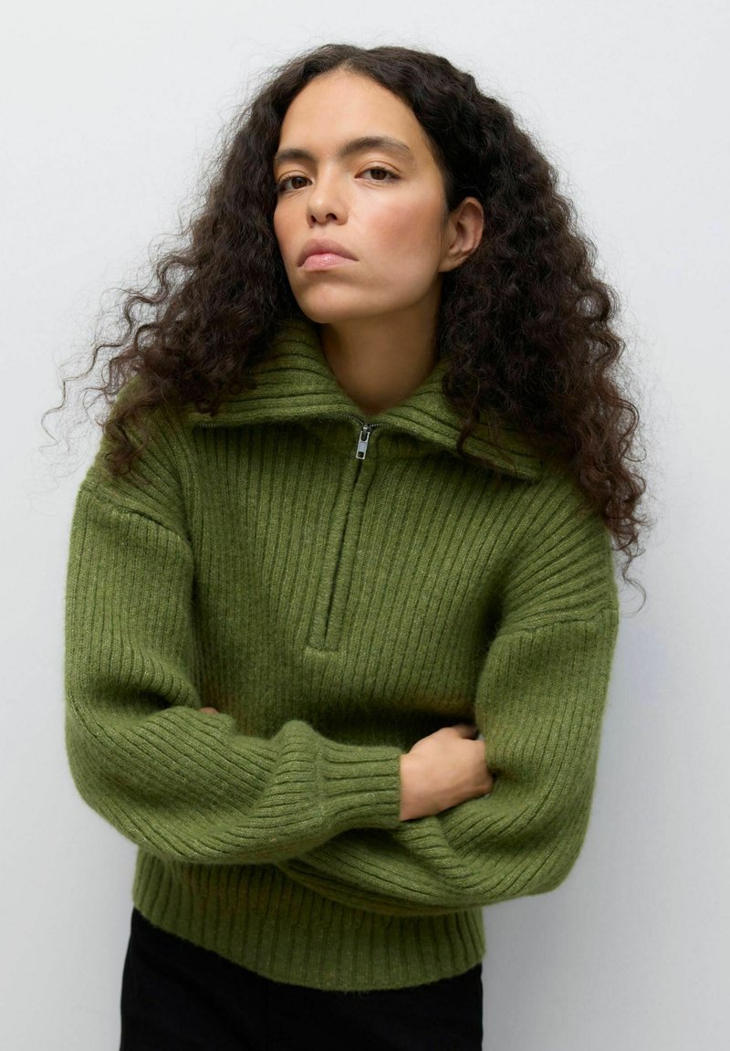 Maglione verde a costine con colletto alto e zip frontale. Presenta maniche ampie e orlo aderente. Realizzato in materiale a maglia testurizzato.