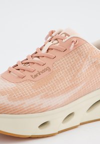 Chaussure de sport rose clair en mesh avec un motif en grille, dotée d'une semelle épaisse crème et d'accents beiges, ainsi que de lacets plats.