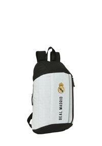 Zaino bianco e nero con una texture liscia, dotato del logo del Real Madrid, particolari neri e un compartimento con cerniera.